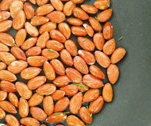 Almonds roasted in a pan lined with olive oil and rosemary